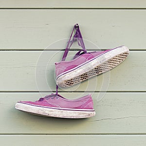 Pair of red old wornout sneakers hanging on the wall photo