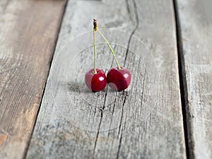 Pair of red ripe cherries on rustic weathered wooden table