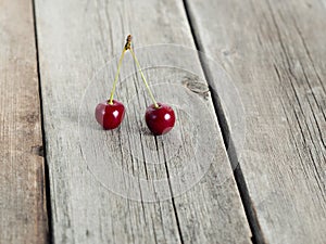 Pair of red ripe cherries on rustic weathered wooden table