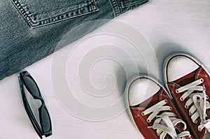 Pair of red sneakers, retro fragment jeans, black sunglasses on