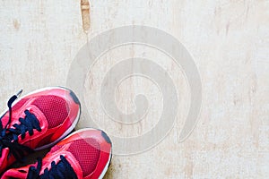 Pair of red sport shoes laid on grunge wooden floor background,