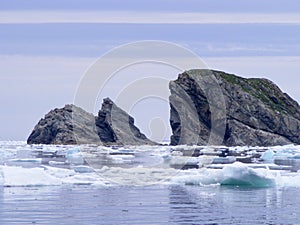 Pair of rugged rock islets next to iceberg chunks in Twillingate Harbour