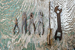 Pair of rusted pliers wrench and srewdriver isolated on on a pelling paint plywood