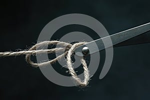 A pair of scissors is cutting a piece of string