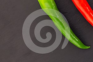Pair of sharp peppers pepper red green chili part of a vegetable decoration culinary design on a black background, slate base copy