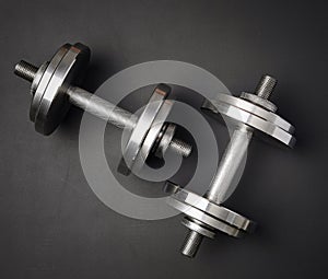 pair of shiny steel typesetting dumbbells for bodybuilding on a black background