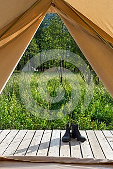 Pair of shoes near canvas tent at forest