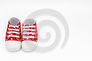 pair of shoes for newborn babies in red with white dots in front of insulated white background and copy space