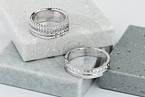 Pair of silver wedding rings with geometric shapes on gray background