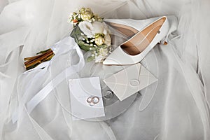 a pair of wedding shoes , a bouquet of flowers , a wedding invitation , and a pair of wedding rings