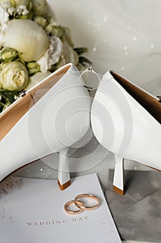 a pair of wedding shoes , a bouquet of flowers , a wedding invitation , and a pair of wedding rings