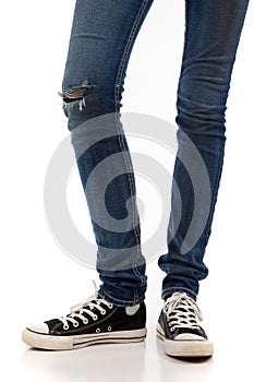 Legs with jeans and retro black sneakers on a white background