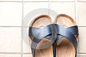 A pair of slipper on skin of black on beige tiles background