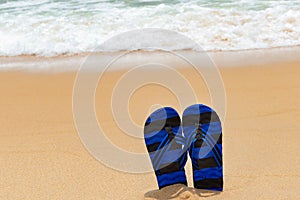Pair of slippers in front of a beach with wave