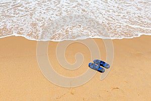 Pair of slippers in front of a beach with wave
