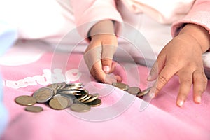 A pair of small hands are playing with euro coins