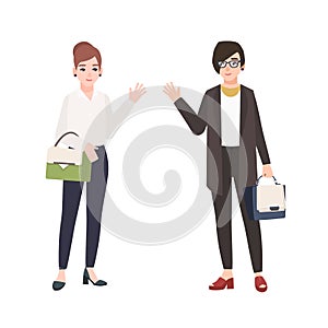 Pair of smiling women dressed in business clothes or female office workers greet each other. Friendly colleagues