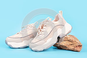 Pair of sneakers stand on a stone on blue background close-up side view.