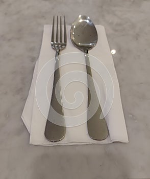 a pair of spoons and forks on a white tissue on a marble table. Sekective focus. Isolated background