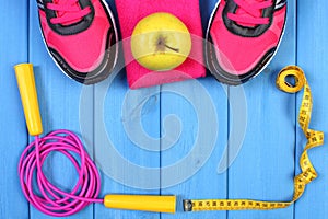 Pair of sport shoes, fresh apple and accessories for fitness on blue boards copy space for text