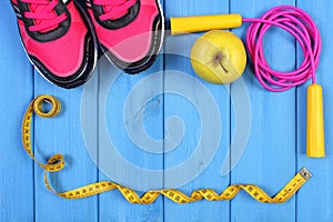 Pair of sport shoes, fresh apple and accessories for fitness on blue boards, copy space for text