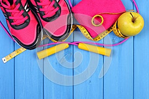 Pair of sport shoes, fresh apple and accessories for fitness on blue boards, copy space for text