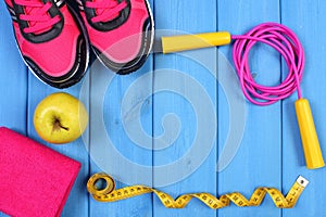 Pair of sport shoes, fresh apple and accessories for fitness on blue boards, copy space for text