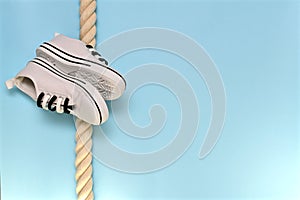 A pair of sports shoes obliquely on a rope.