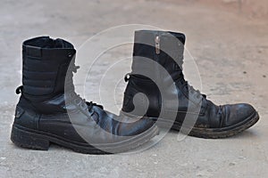 Pair of sturdy used leather boots on grey background, old shoes