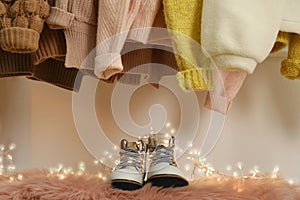 Pair of stylish female boots and different warm clothes indoors