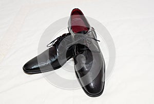 Pair of stylish men`s shoes on a white cloth surface.