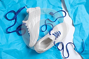 Pair of stylish shoes with laces on light blue paper, flat lay