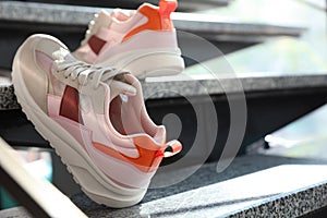 Pair of stylish women`s sneakers on marble stairs indoors