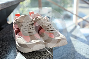 Pair of stylish women`s sneakers on marble stairs indoors