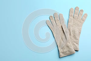 Pair of stylish woolen gloves on light blue background, flat lay. Space for text