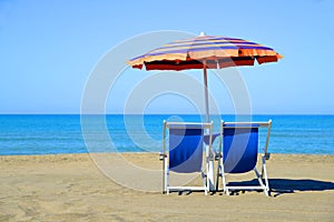 Pair of sun loungers and sunshade umbrella on the beach.