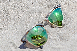 Pair Of Sunglasses On The Beach With A Reflection Of A Beautiful