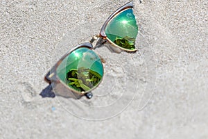 Pair Of Sunglasses On The Beach With A Reflection Of A Beautiful