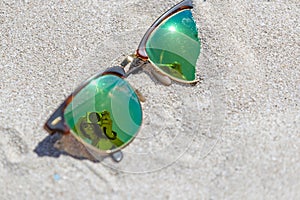 Pair Of Sunglasses On The Beach With A Reflection Of A Beautiful