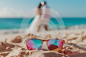 A pair of sunglasses is laying on the sand at the beach