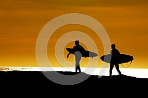 Pair of surfers heading out in the sunset photo