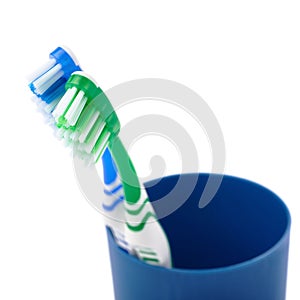 Pair of toothbrushes in blue plastic cup isolated over white background