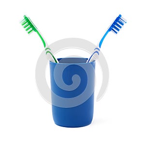 Pair of toothbrushes in blue plastic cup isolated over white background