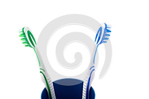 Pair of toothbrushes in blue plastic cup isolated over white background