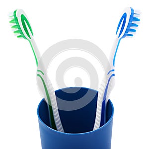 Pair of toothbrushes in blue plastic cup isolated over white background