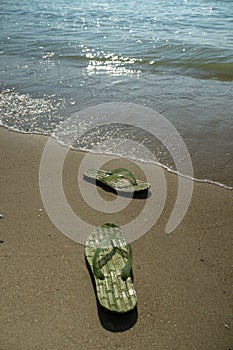 Pair, two of men`s beach slippers on the sand