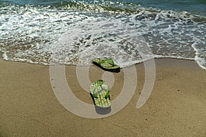 Pair, two of men`s beach slippers on the sand