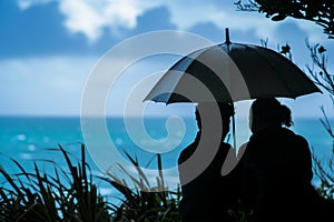 pair under an umbrella, ocean in the backdrop