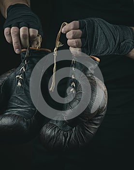 Pair of very old boxing sports gloves in men`s hands