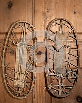 A pair of very old snowshoes hanging on a wooden wall